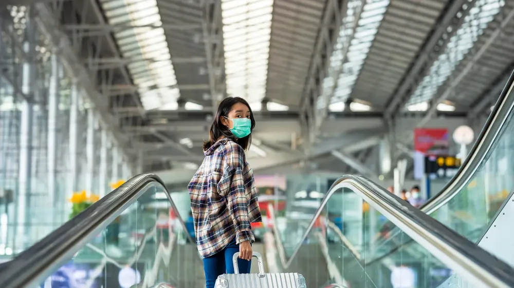 Asian woman tourist wearing face mask protection from coronavirus walking in the airport